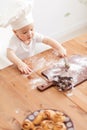 Happy cute little baby boy in a cook cap playing with flour at home kitchen Royalty Free Stock Photo