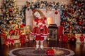 Happy cute little blonde girl with long hair in a red dress, waiting for Christmas and New year opens a gift on the Royalty Free Stock Photo