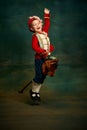 Happy cute little boy dressed up as medieval little prince and pageboy ride toy horse over dark vintage style background