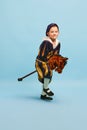 Happy cute little boy dressed up as medieval little prince and pageboy ride toy horse over light blue background Royalty Free Stock Photo