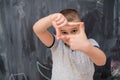 Happy boy making hand frame gesture in front of chalkboard Royalty Free Stock Photo