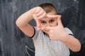 Happy boy making hand frame gesture in front of chalkboard Royalty Free Stock Photo