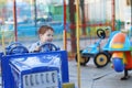 Happy cute little boy rides on car of carousel