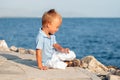 Happy cute little boy sitting on sand at beach Royalty Free Stock Photo