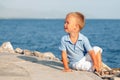 Happy cute little boy sitting on sand at beach Royalty Free Stock Photo