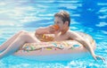 Happy cute little boy teenager lying on inflatable donut ring with orange in swimming pool. Active games on water, vacation Royalty Free Stock Photo