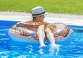 Happy cute little boy teenager lying on inflatable donut ring with orange in swimming pool. Active games on water, vacation Royalty Free Stock Photo