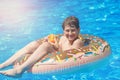 Happy cute little boy teenager lying on inflatable donut ring with orange in swimming pool. Active games on water, vacation Royalty Free Stock Photo