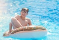 Happy cute little boy teenager lying on an inflatable donut ring in swimming pool. Active games on water, vacation, holidays