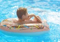 Happy cute little boy teenager lying on an inflatable donut ring in swimming pool. Active games on water, vacation, holidays Royalty Free Stock Photo