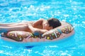 Happy cute little boy teenager lying on an inflatable donut ring in swimming pool. Active games on water, vacation, holidays