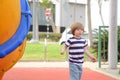 Happy cute little child boy having fun on a yellow slide outdoor in the park, sunny summer day in children playground. Royalty Free Stock Photo