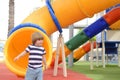 Happy cute little child boy having fun on a yellow slide outdoor in the park, sunny summer day in children playground. Royalty Free Stock Photo