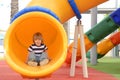 Happy cute little child boy having fun on a yellow slide outdoor in the park, sunny summer day in children playground. Royalty Free Stock Photo