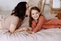 Happy cute little girl with a beautiful young mother lie on the bed Royalty Free Stock Photo