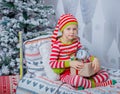 Happy cute little girl dressed in striped pajamas sitting in decorated New Year room at home. Royalty Free Stock Photo