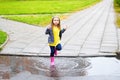 Happy cute little girl jumping in puddle after rain in summer Royalty Free Stock Photo