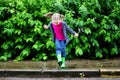 Happy cute little girl jumping in puddle after rain in summer Royalty Free Stock Photo