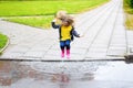 Happy cute little girl jumping in puddle after rain in summer Royalty Free Stock Photo