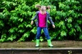 Happy cute little girl jumping in puddle after rain in summer Royalty Free Stock Photo