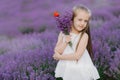 Happy cute little girl in lavender field holding bouquet of purple flowers. Royalty Free Stock Photo