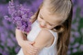 Happy cute little girl in lavender field holding bouquet of purple flowers. Royalty Free Stock Photo