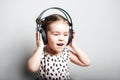 Happy Cute little girl in pink dress listening music in headphones on grey background Royalty Free Stock Photo
