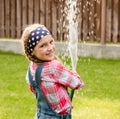 Happy cute little girl pouring water from a hose Royalty Free Stock Photo
