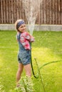 Happy cute little girl pouring water from a hose