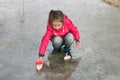 Happy cute little girl in rain boots playing with handmade ships in the spring water puddle Royalty Free Stock Photo