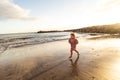 Happy cute little girl running in sand on beautiful beach during sunset. Summer holidays Royalty Free Stock Photo