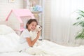 Happy cute girl sitting on the bed in her children`s room and hugs Teddy bear Royalty Free Stock Photo