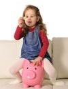 Happy Cute little girl sitting on huge piggy bank inserting Coin