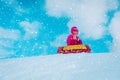 Happy cute little girl slide in winter snow