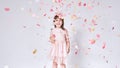 Happy cute little girl wearing pink dress in tulle with princess crown on head on white background playing with confetti Royalty Free Stock Photo