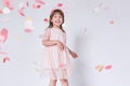 Happy cute little girl wearing pink dress in tulle with princess crown on head on white background playing with confetti