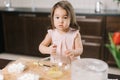 Happy cute little girl wearing white dress is whisking eggs in mixing bowl with fork Royalty Free Stock Photo