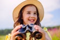 Happy cute little girl 4-5 years old stands in nature , holds binoculars Royalty Free Stock Photo