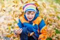 Happy cute little kid boy with autumn leaves playing in garden Royalty Free Stock Photo