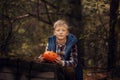 Happy cute little kid boy with halloween pumpkin in autumn dark forest.