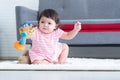 Happy cute little 7 months old multiracial, asian and caucasian, newborn baby girl sitting on floor in living room at home. Royalty Free Stock Photo