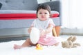 Happy cute little 7 months old multiracial, asian and caucasian, newborn baby girl sitting on floor in living room at home, Royalty Free Stock Photo