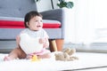 Happy cute little 7 months old multiracial, asian and caucasian, newborn baby girl sitting on floor in living room at home, Royalty Free Stock Photo