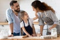 Happy cute little preschool girl spreading flour on cheerful parents.