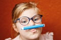 Happy cute little preschooler girl with glasses holding colorful pencils and making gesture while looking at camera Royalty Free Stock Photo