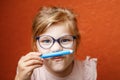 Happy cute little preschooler girl with glasses holding colorful pencils and making gesture while looking at camera Royalty Free Stock Photo