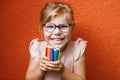 Happy cute little preschooler girl with glasses holding colorful pencils and making gesture while looking at camera Royalty Free Stock Photo