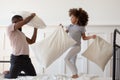 Happy cute mixed race girl fighting pillows with dad. Royalty Free Stock Photo