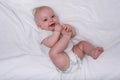 Happy cute 3 month baby girl with short blond hair lying on the white cloth nappy. Newborn diapers