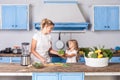 Happy cute mother in apron and little daughter holding broccoli and smiling, healthy vegan nutrition Royalty Free Stock Photo